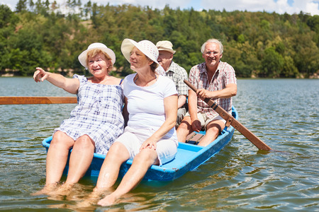 Senior group makes a trip in the rowboat on the lake as a restの写真素材