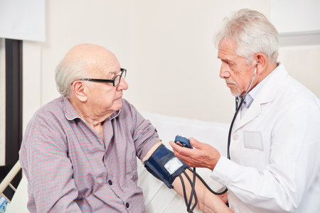 Doctor measuring blood pressure in an old man as a control in hypertensionの写真素材
