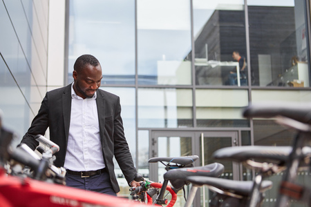 African businessman with bicycle in front of the corporation or office buildingの写真素材
