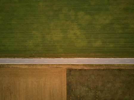 Empty highway in autumn from above through field and meadow