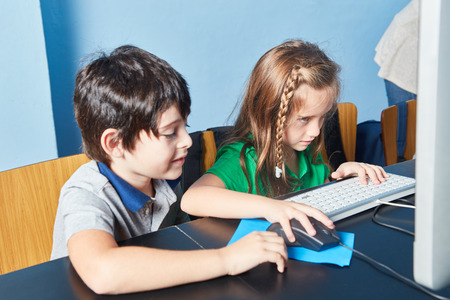 Two children learn concentrated at the computer in computer science lessons