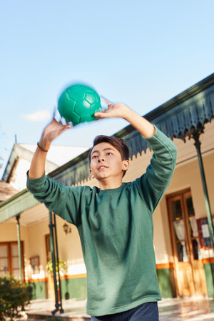 Boy as a student throws a ball in the schoolyard in physical educationの写真素材
