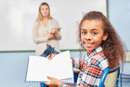 Schoolgirl proudly shows her notebook with the homework in elementary school