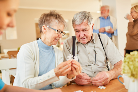 Senior couple with dementia playing puzzle in retirement home or nursing homeの写真素材