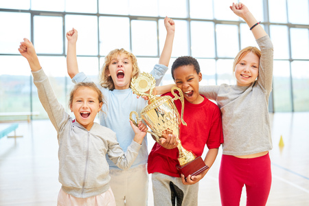 Cheering children as a successful student team with trophy after a competitionの写真素材