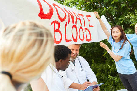 Team activists advertise blood donation with a Donate Blood posterの写真素材