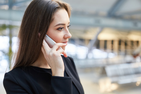 Business woman makes a phone call at the airport terminal before departing on her business trip
