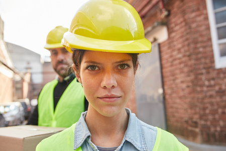 Young woman as apprentice in training in logistics profession with safety helmet