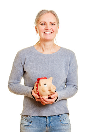 Smiling senior woman is holding piggy bank in hands as a finances conceptの写真素材