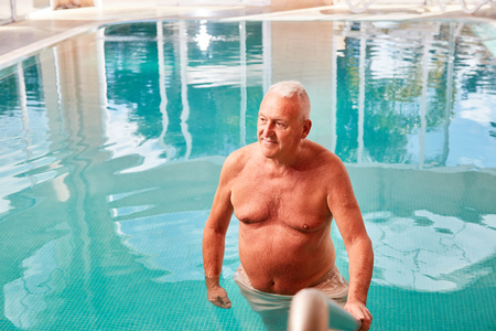Senior man as a relaxed retiree in the swimming pool on a spa vacationの写真素材