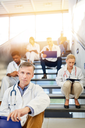Group of doctors and nurses sitting in the break on stairs in a clinicの写真素材