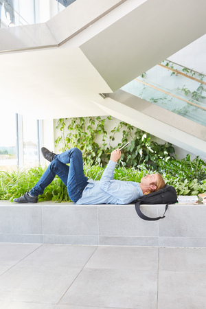 Student reads text in tablet computer in his class breakの写真素材