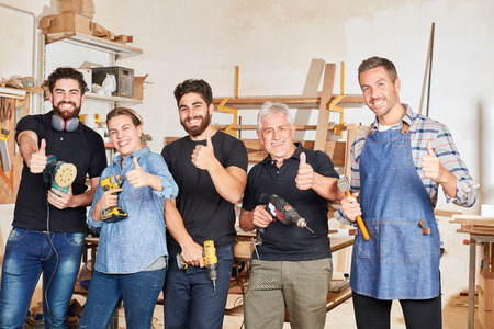 Successful carpenter team with thumbs up in the carpentry or joinery