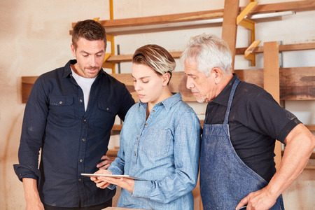 Schreiner team with trainee planning with tablet computer in the joineryの写真素材