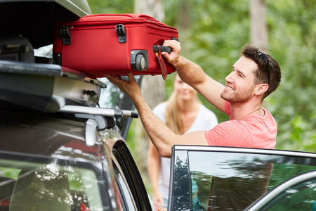 Man packs suitcases in the roof box on the car before traveling on vacationの写真素材