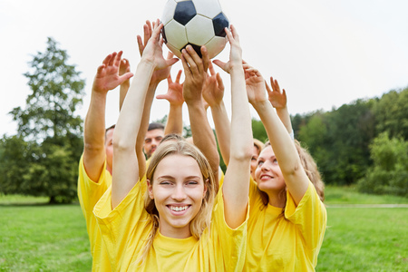 Young woman and her team are doing teamwork training with the footballの写真素材