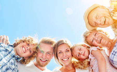 Happy extended family in three generations in front of a blue sky