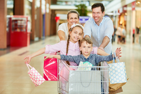 Parents and children shopping in the shopping cart have fun in the shopping centerの写真素材