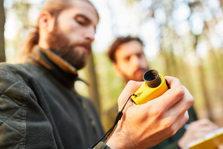 Two foresters work with the rangefinder to measure the height of the treeの写真素材