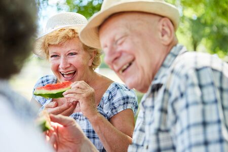 Happy senior couple on a nature outing while eating melonの写真素材