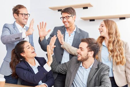 Group of young business people gives themselves the high five and celebrates a success