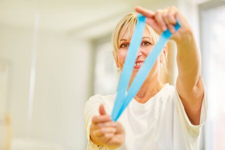 Doctor or non-medical practitioner tests the blue elastic band Kinesio Tape in chiropractic