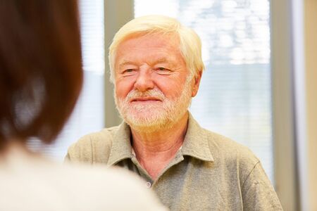 Senior man as a patient talking to a female doctor or therapist during the consultation