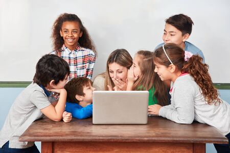 Group of kids laughing and joking with teacher in computer lessonの写真素材
