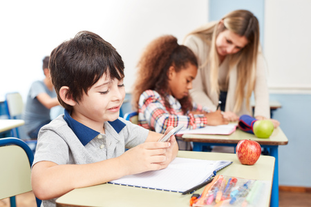 Student reads or writes a text message on the smartphone in classの写真素材