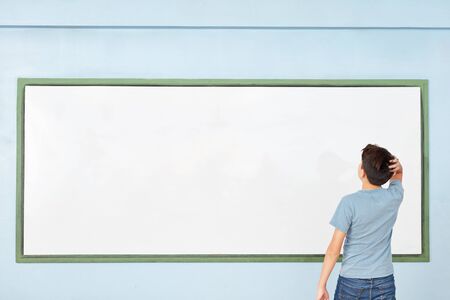 Pupil in front of whiteboard considering solution in a test at schoolの写真素材
