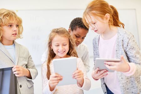 Group of kids in elementary school learn in teamwork with the tablet computer
