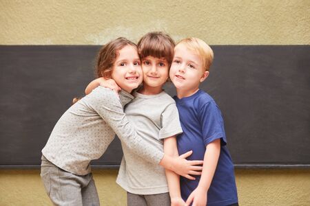 Three children hug as friends in elementary or kindergartenの写真素材
