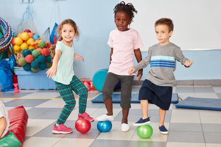 Three children as friends in international kindergarten play together with balls