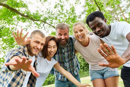 Happy multicultural group of students and friends while waving in the parkの写真素材