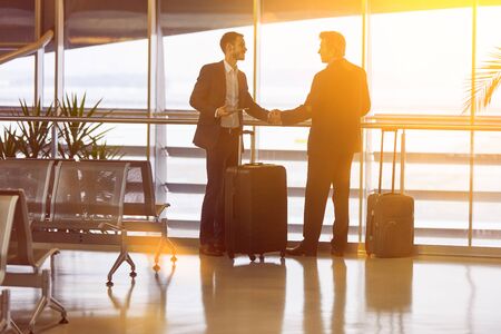 Two businessmen greet each other with handshake at the airport in summerの写真素材
