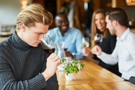 Young man at a wine tasting with a glass of red wine checks the bouquet