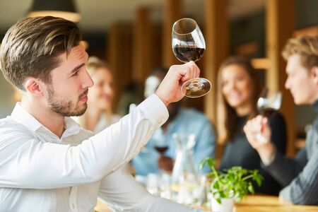 Young man with wine glass at a wine tasting proves quality of red wineの写真素材