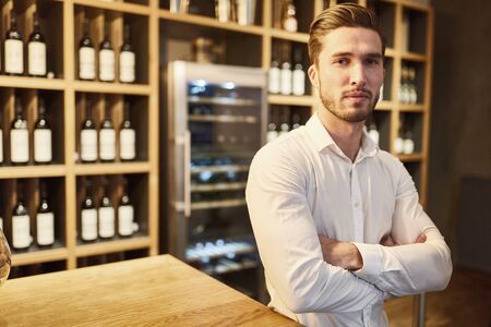 Young man as a wine merchant or sommelier in a wine shop or barの写真素材