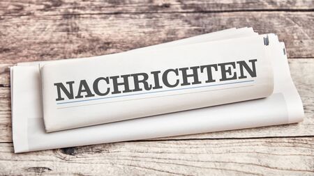 Newspaper with German word "Nachrichten" (news) on a wooden tableの写真素材