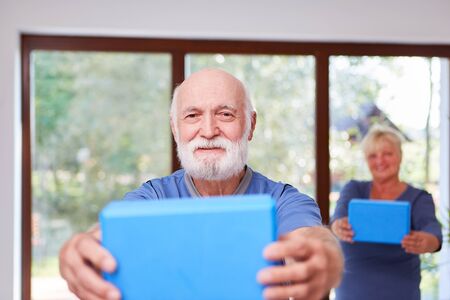 Vital senior man does a healthy back exercise in rehab gymnastics courseの写真素材