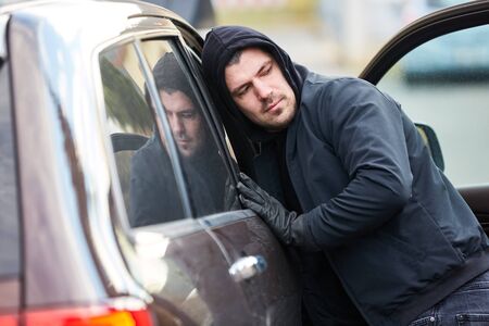 Man as a thief at the open door of a carの写真素材