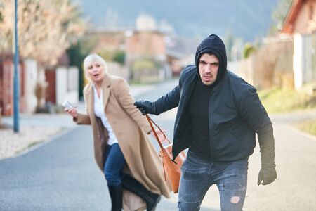 Thief on the run after stealing a handbag from woman in the streetの写真素材