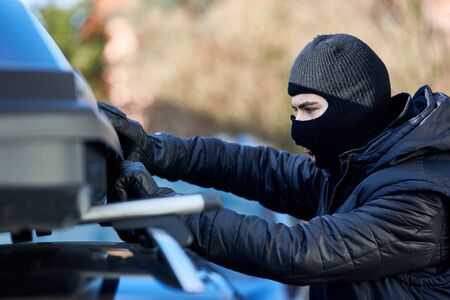 Thief wants to open lock of roof rack or roof box on a car