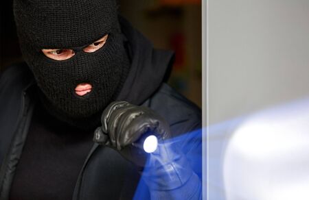 Burglar breaking in house at night with flashlightの写真素材