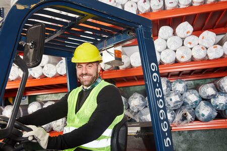 Warehouse worker as a forklift driver works on the forklift in the warehouse