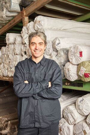 Smiling man as a warehouse specialist in warehouse with crossed armsの写真素材