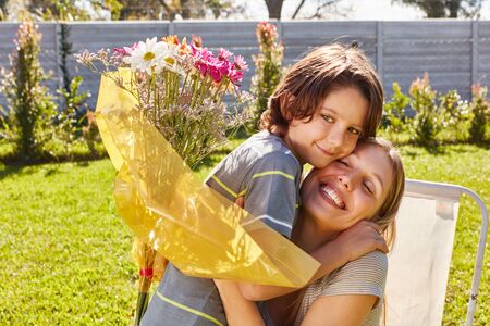 Son gives his mother a bouquet of flowers on Mother's Day or birthdayの写真素材