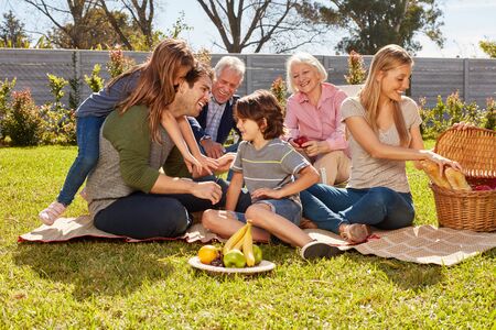 Family with children and grandparents celebrates birthday and makes a picnicの写真素材
