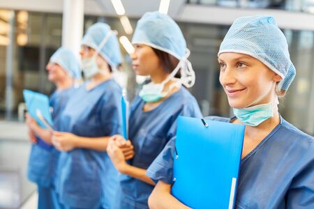 Surgery team with young female doctor in training in blue surgical clothing in emergency roomの写真素材