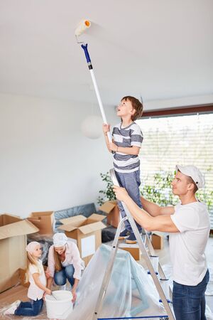 Father helps son on the ladder while stroking the blanket in the new houseの写真素材